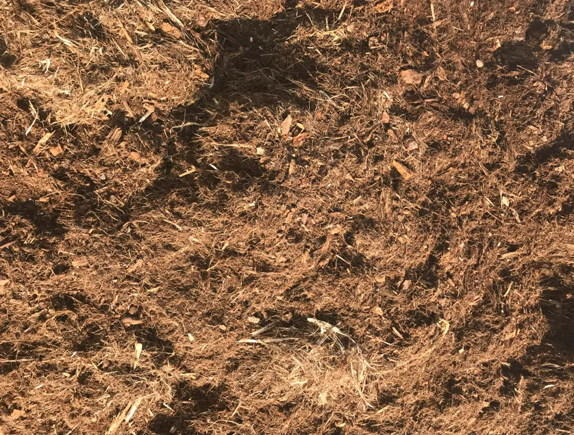 Gros plan sur du paillis brun aux textures variées, pouvant servir au jardinage ou à l'aménagement paysager.