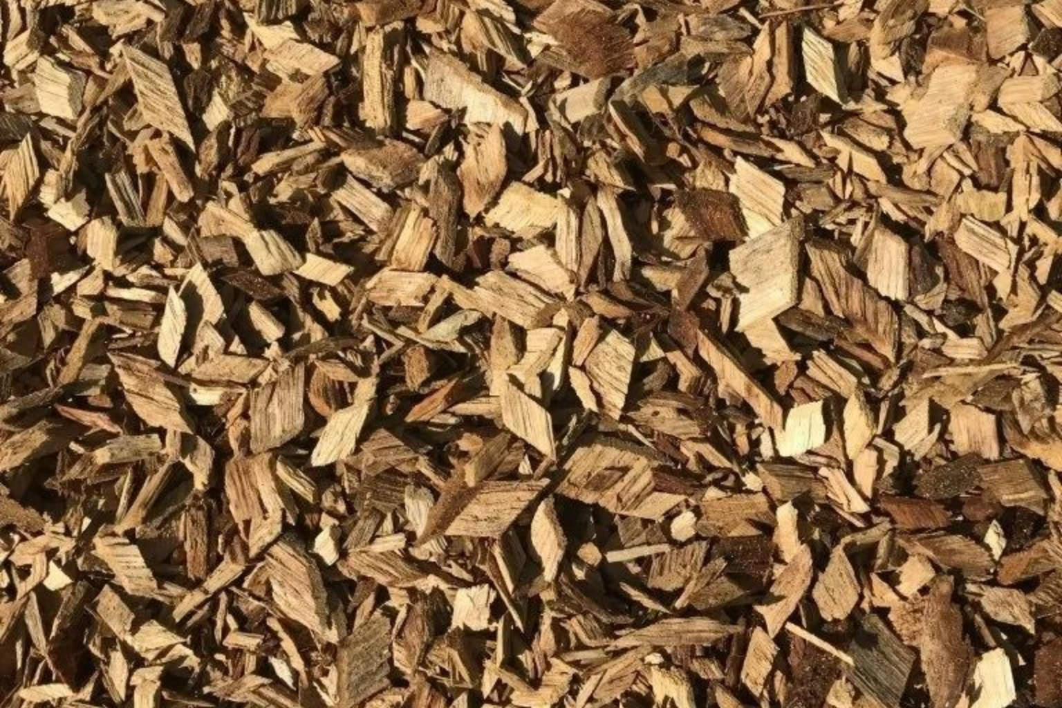 Gros plan sur des copeaux de bois bruns, probablement destinés au paillis ou à l'aménagement paysager.