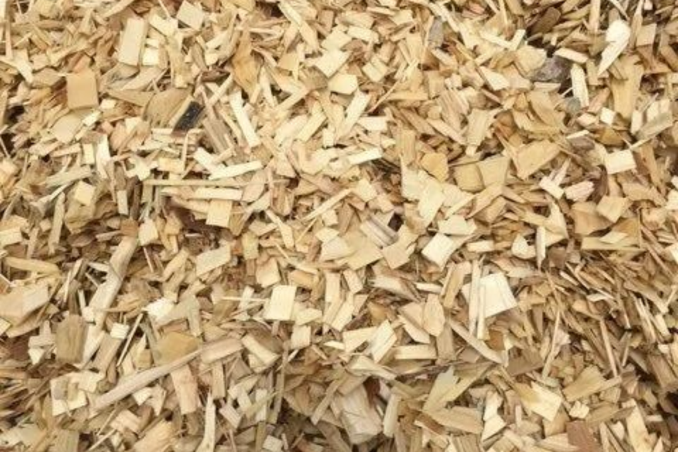 Tas de copeaux de bois clairs, de formes et de tailles variées, probablement destinés à l'aménagement paysager ou au jardinage.