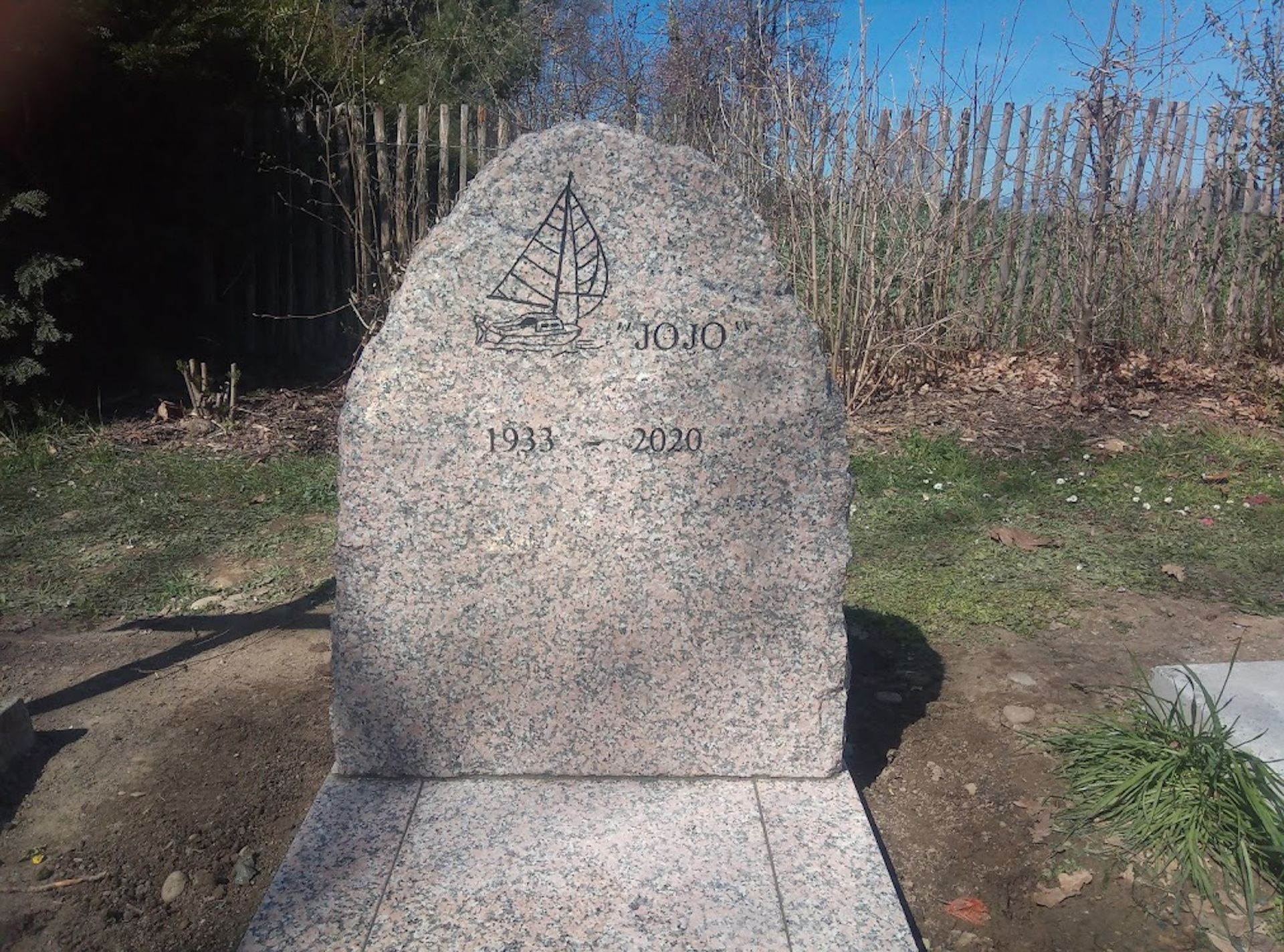 Ein Grabstein auf einem Friedhof mit einem Boot darauf.