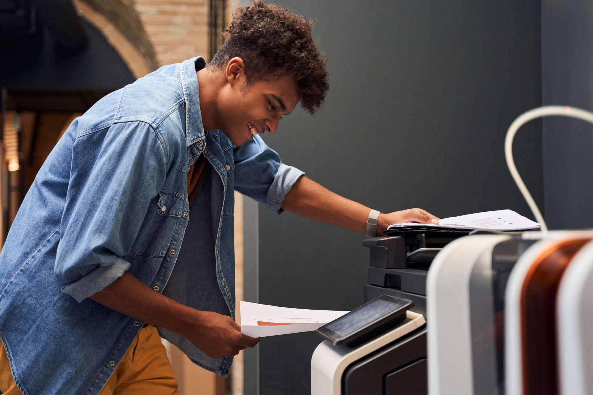 Un hombre está usando una impresora para imprimir un trozo de papel.