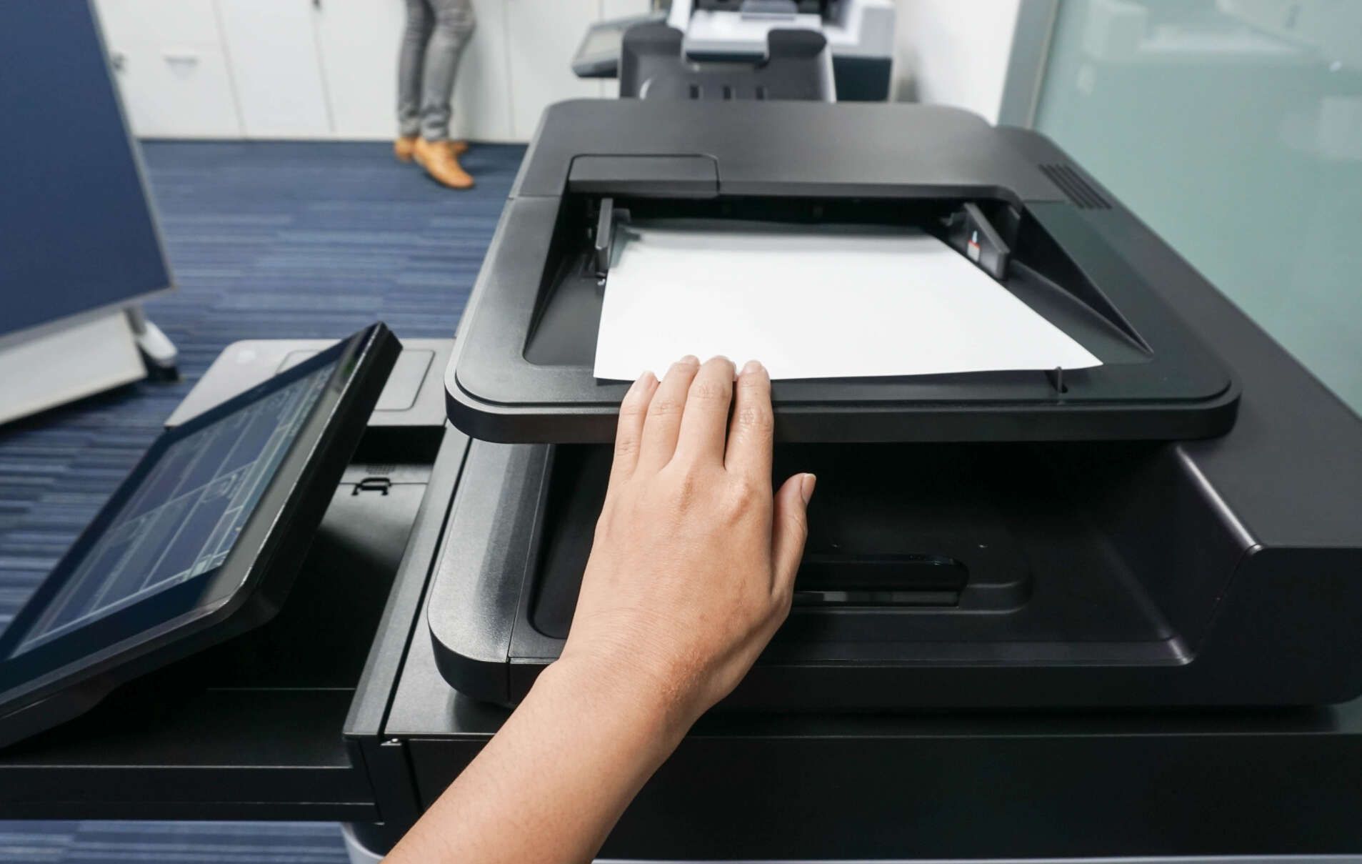 Una persona está usando una impresora para escanear una hoja de papel.