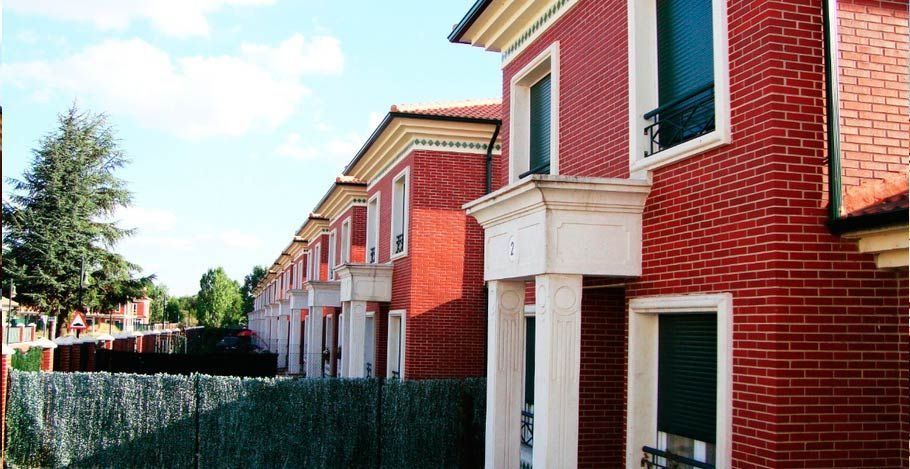 Una hilera de casas de ladrillo rojo con una valla verde delante de ellas.