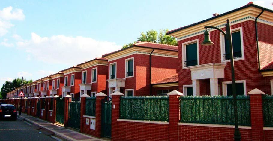 Una hilera de casas de ladrillo rojo con una valla verde