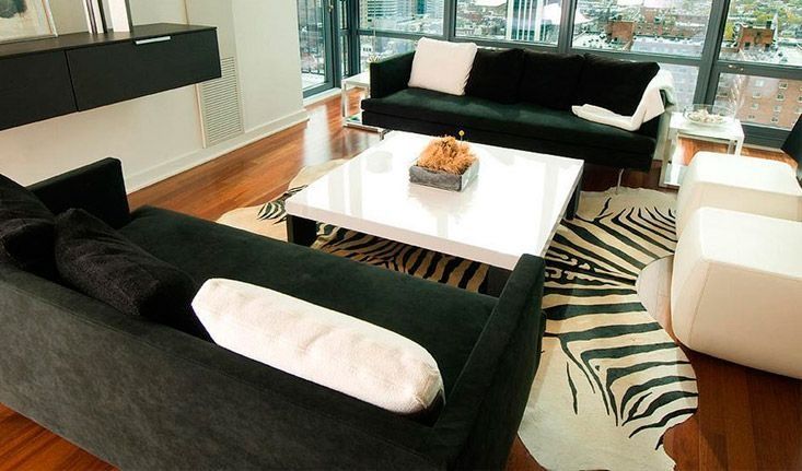 Una sala de estar con muebles en blanco y negro y una alfombra con estampado de cebra.