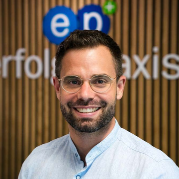 Ein Mann mit Bart und Brille lächelt in die Kamera .
