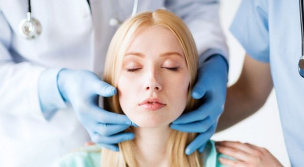 Una mujer está siendo examinada por un médico con los ojos cerrados.