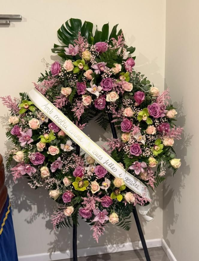 Primer plano de un ramo con una rosa de color melocotón en foco, rodeada de flores rojas, blancas y naranjas.