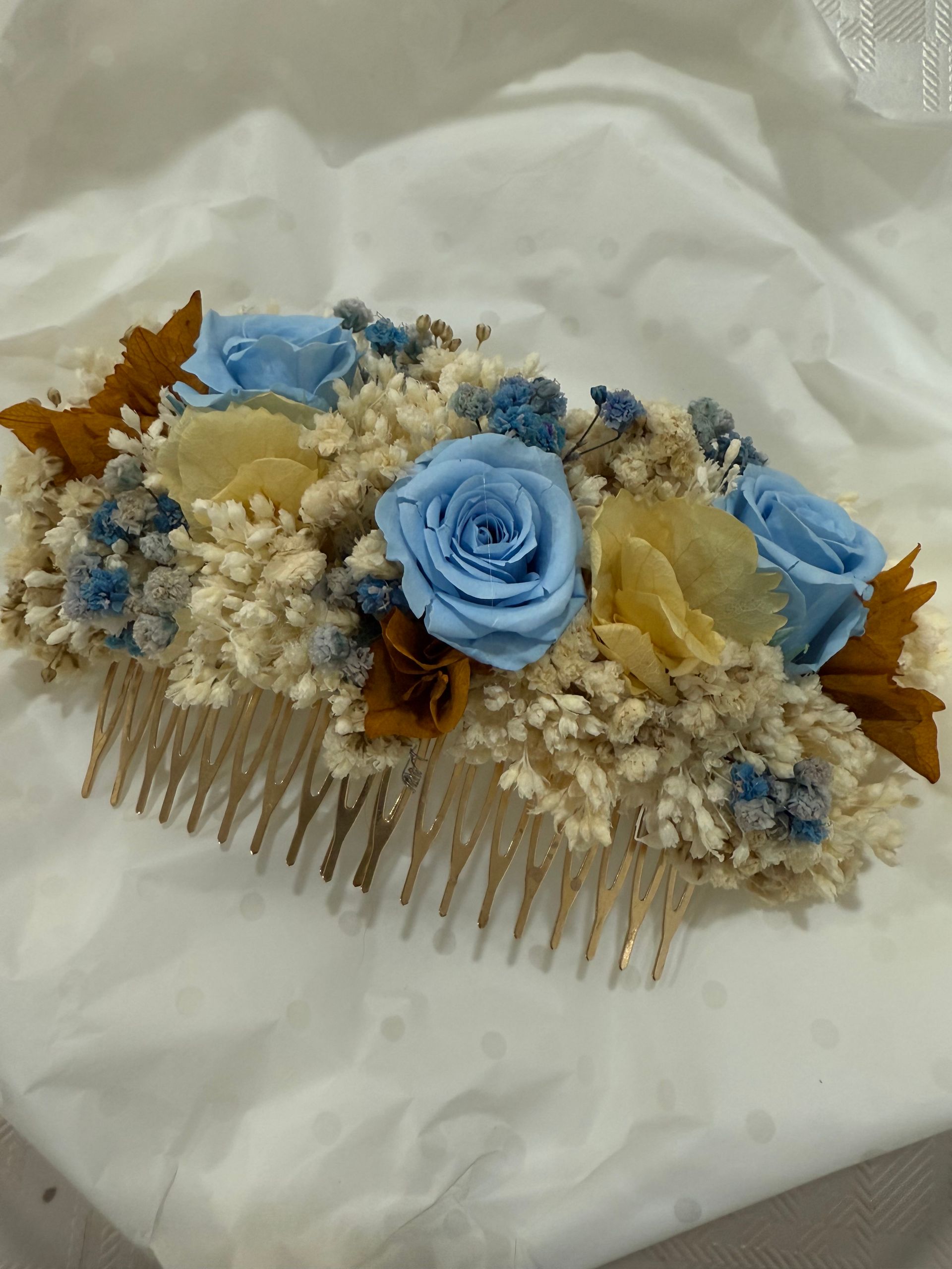 Peineta floral con rosas azules y amarillas, relleno blanco y dientes de peine dorados.