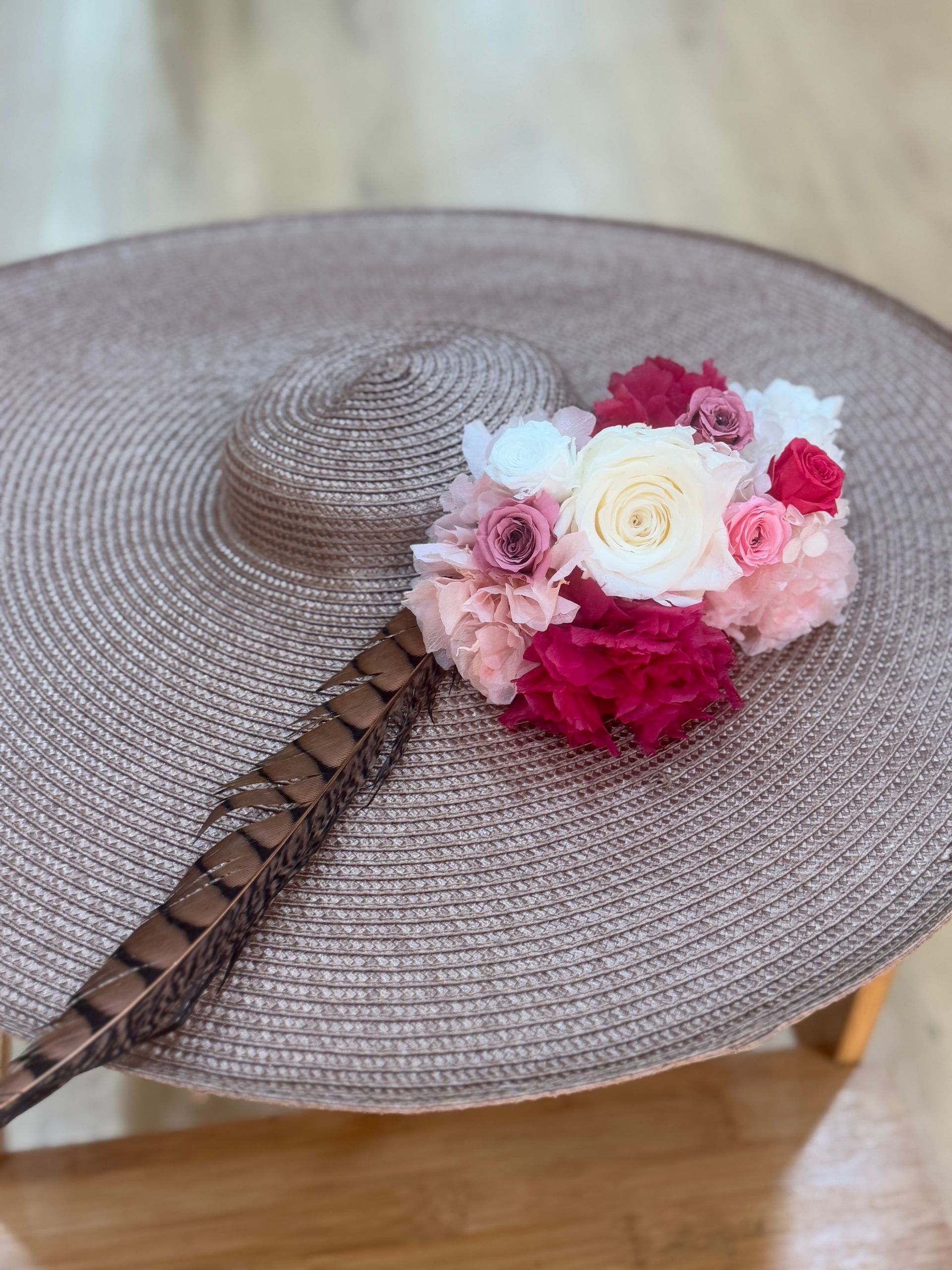 Sombrero para el sol de ala ancha con un pequeño ramo de flores y un detalle de plumas.