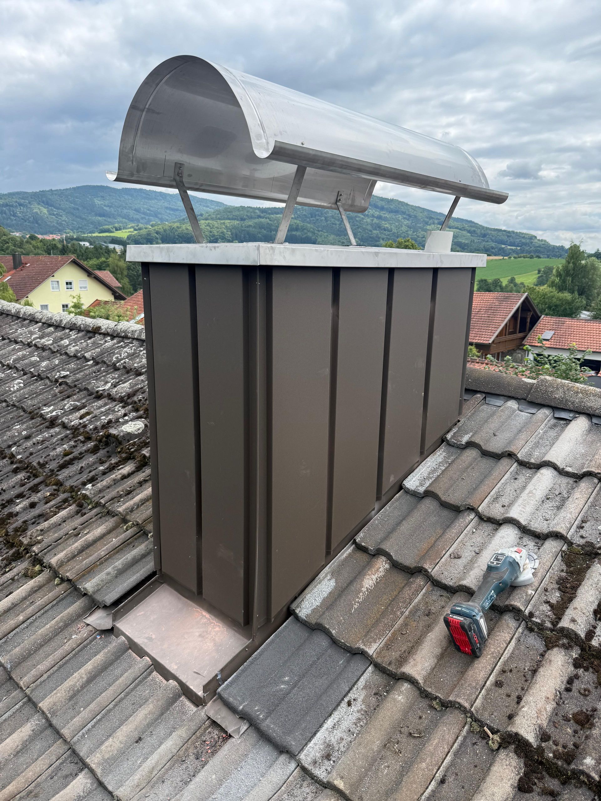 Spenglerarbeiten an einem kleinen Schornstein mit Dach