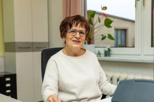 Eine Frau sitzt an einem Schreibtisch vor einem Laptop.