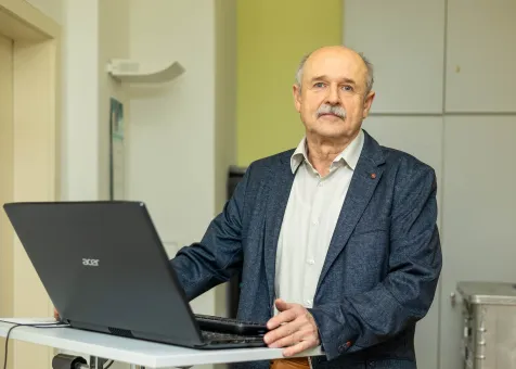 Ein Mann im Anzug steht vor einem Laptop.