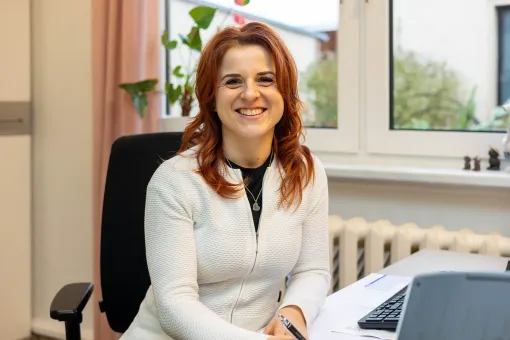 Eine Frau sitzt an einem Schreibtisch vor einem Laptop.