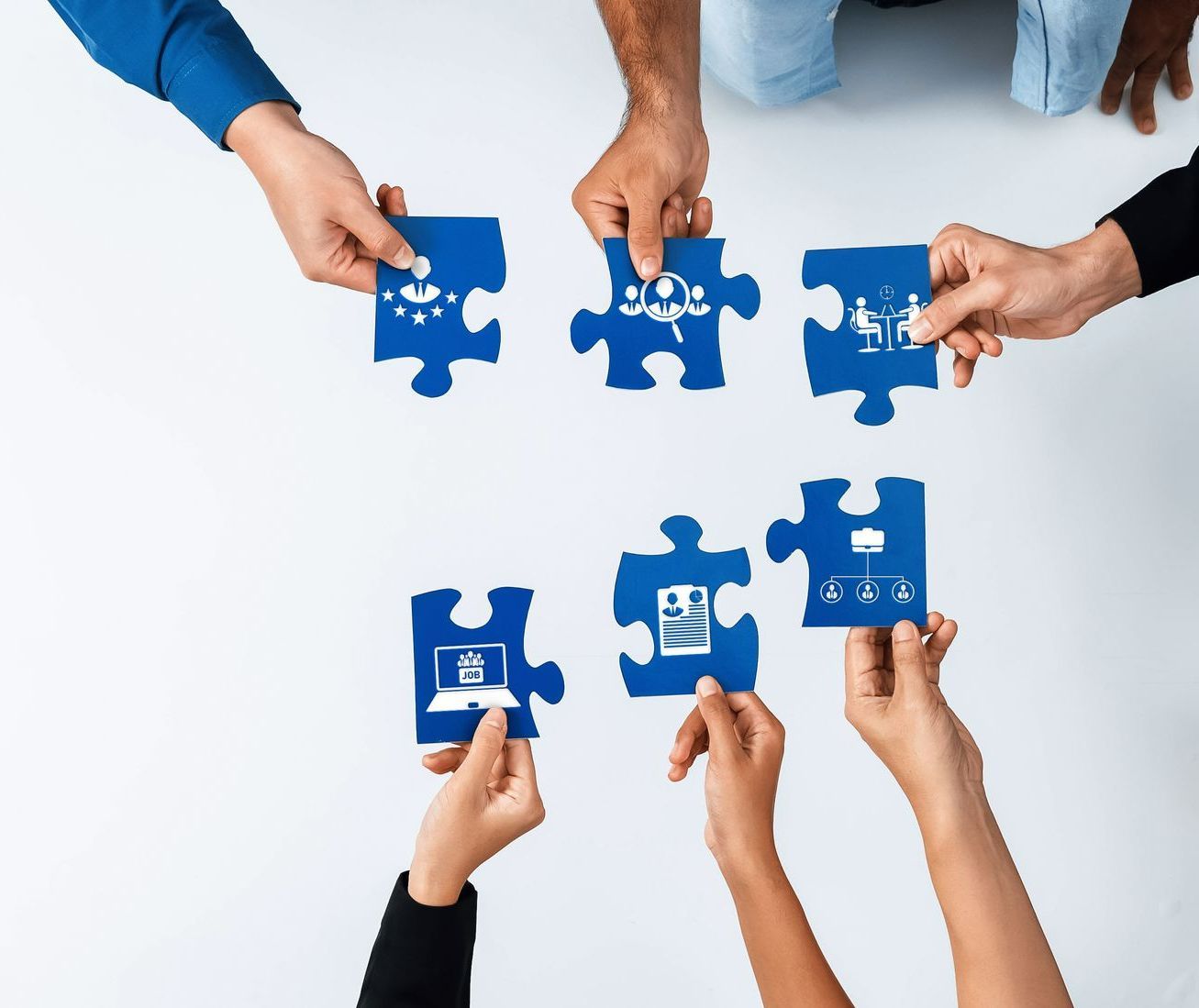 Mains présentant plusieurs pièces d'un puzzle bleu