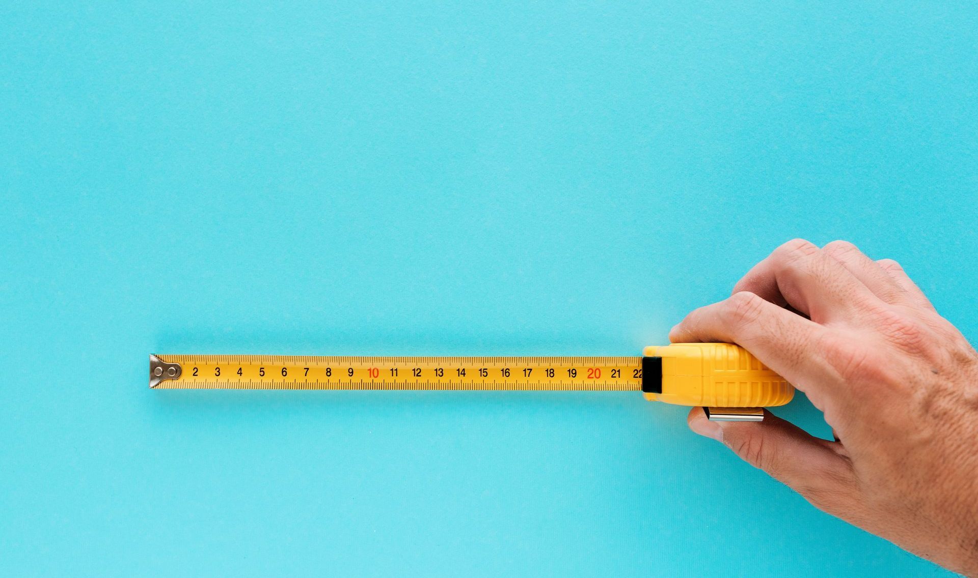 Main tenant un mètre de mesure jaune sur fond bleu