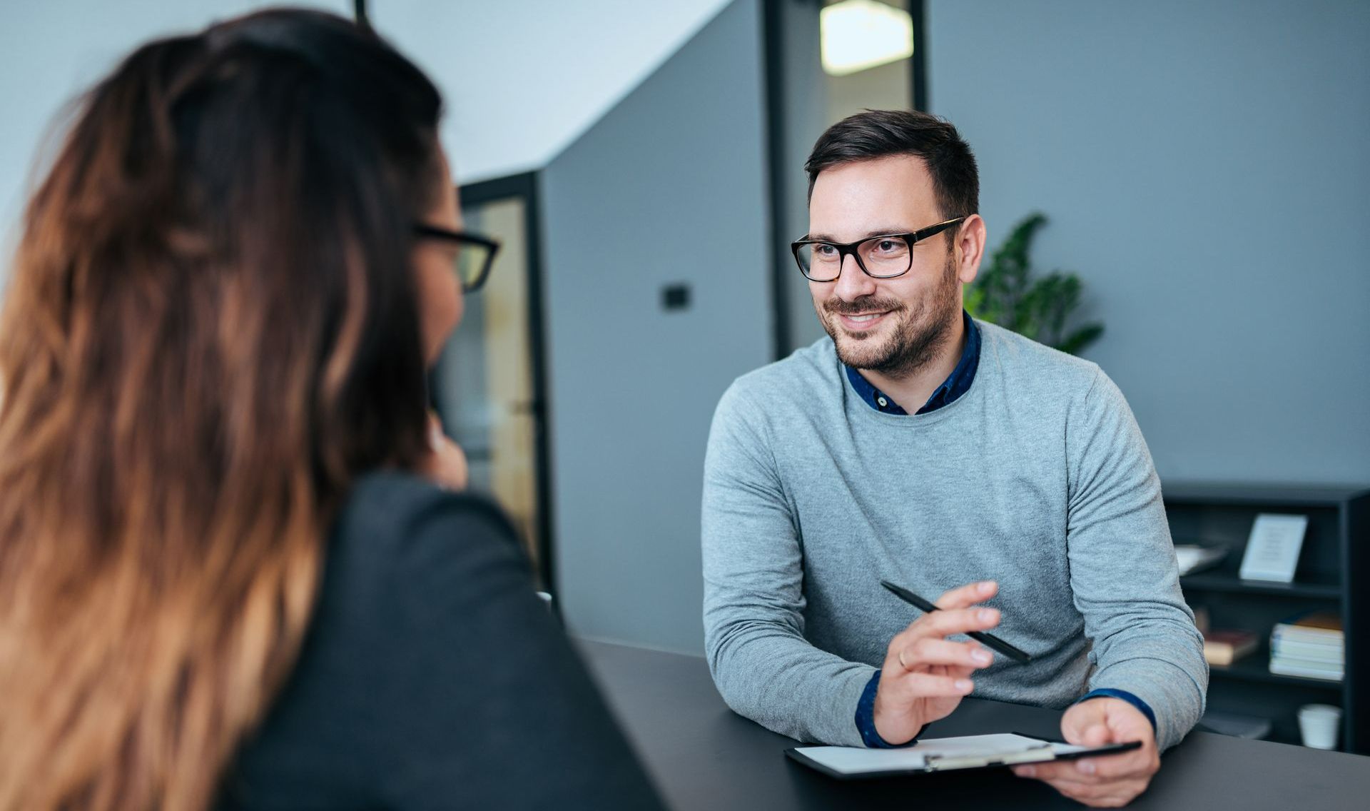 Homme à lunettes échangeant avec une femme autour d'une table