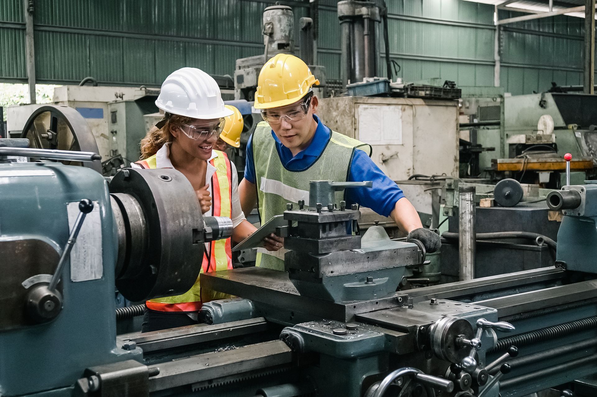 Une femme et un homme portant un casque et utilisant une machine dans une usine