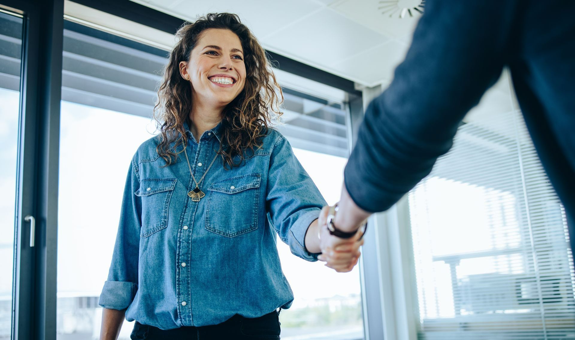 Femme aux cheveux bouclés souriant à une personne