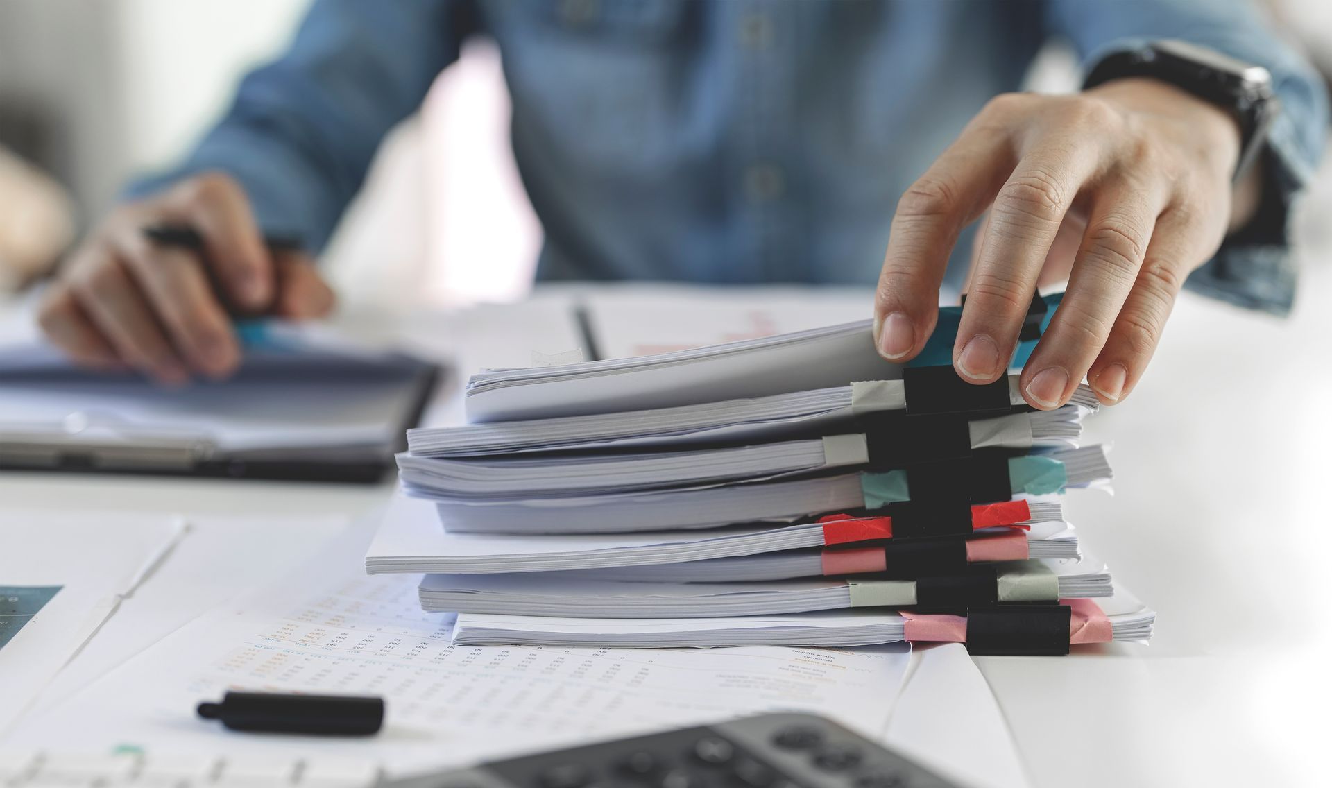 Pile de dossiers sur un bureau saisie par une main