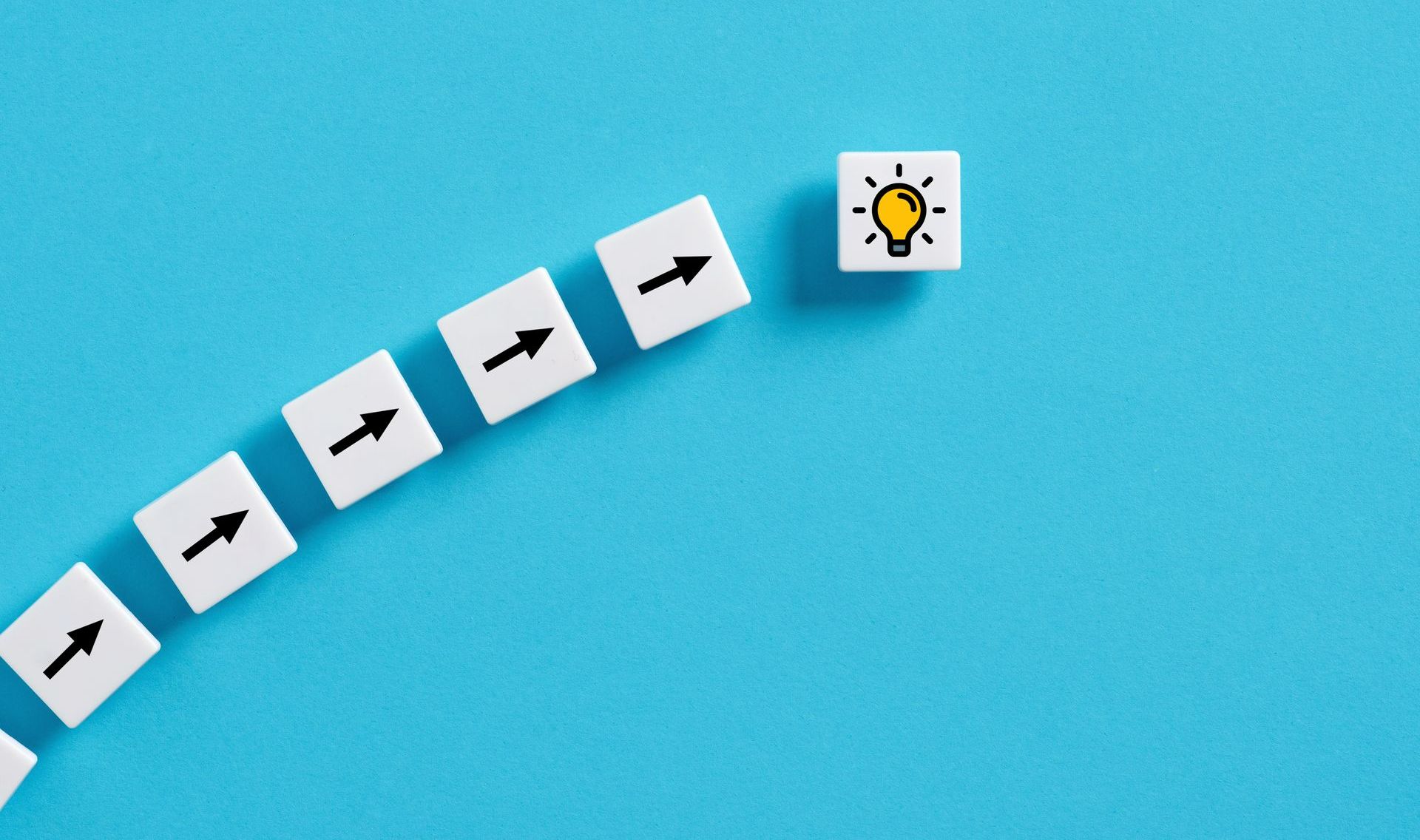 Suite de dés blancs comportant une flèche noire suivis d'un dé blanc comportant une ampoule jaune