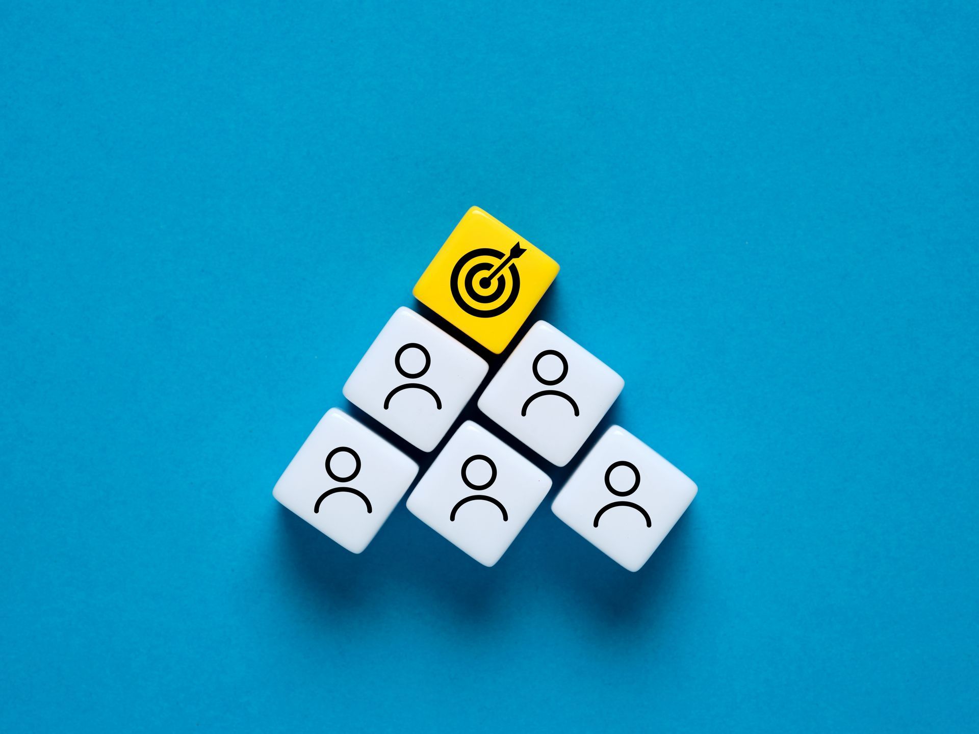 Dé jaune comportant une cible au sommet d'une pyramide de dés blanc comportant des bonshommes