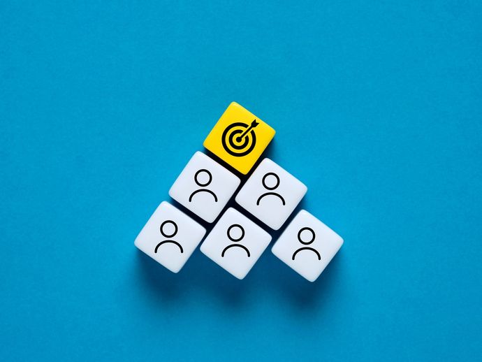 Dé jaune comportant une cible au sommet d'une pyramide de dés blanc comportant des bonshommes