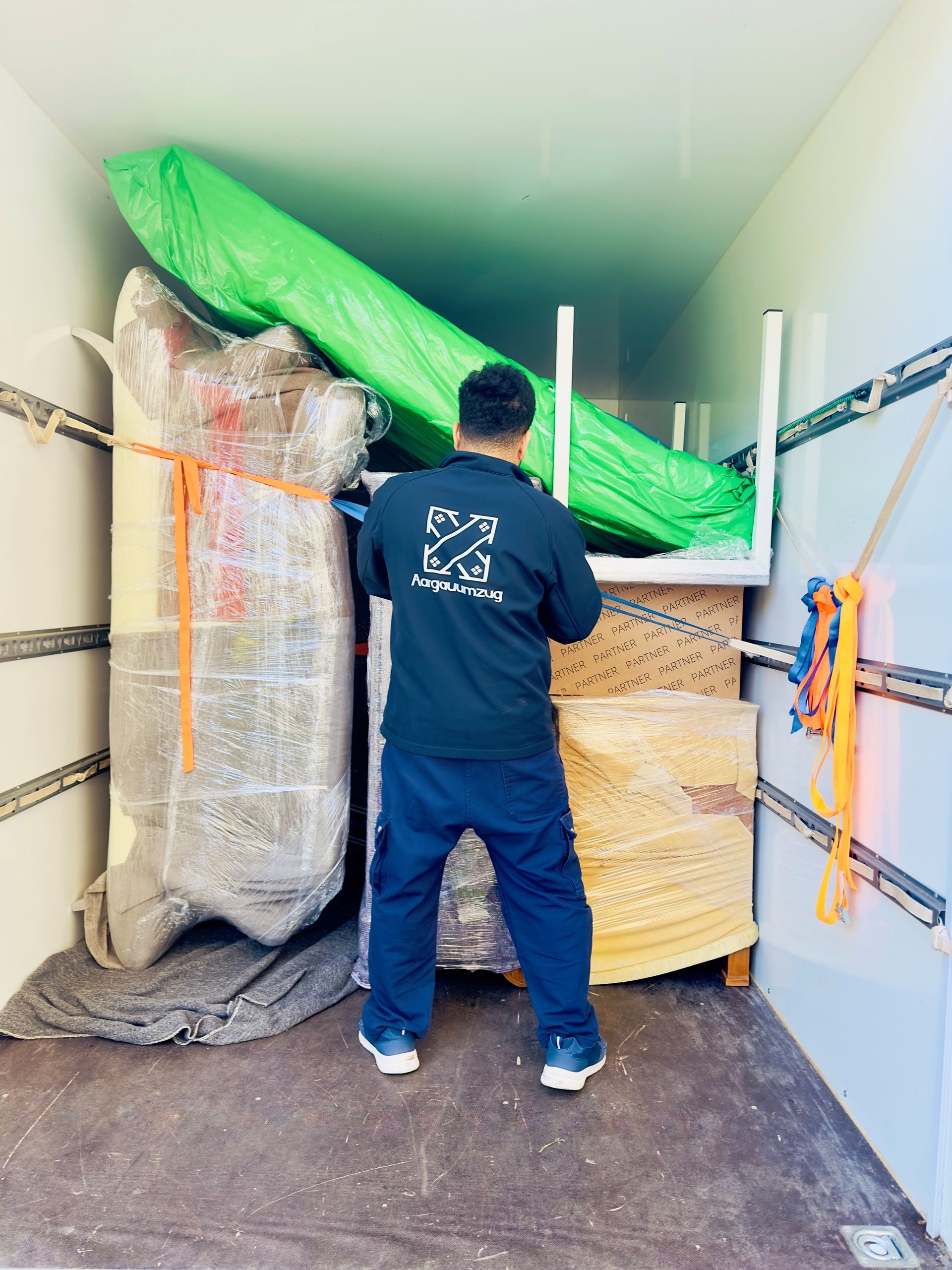 Umzugshelfer mit grünem Verpackungsmaterial in Lagerraum