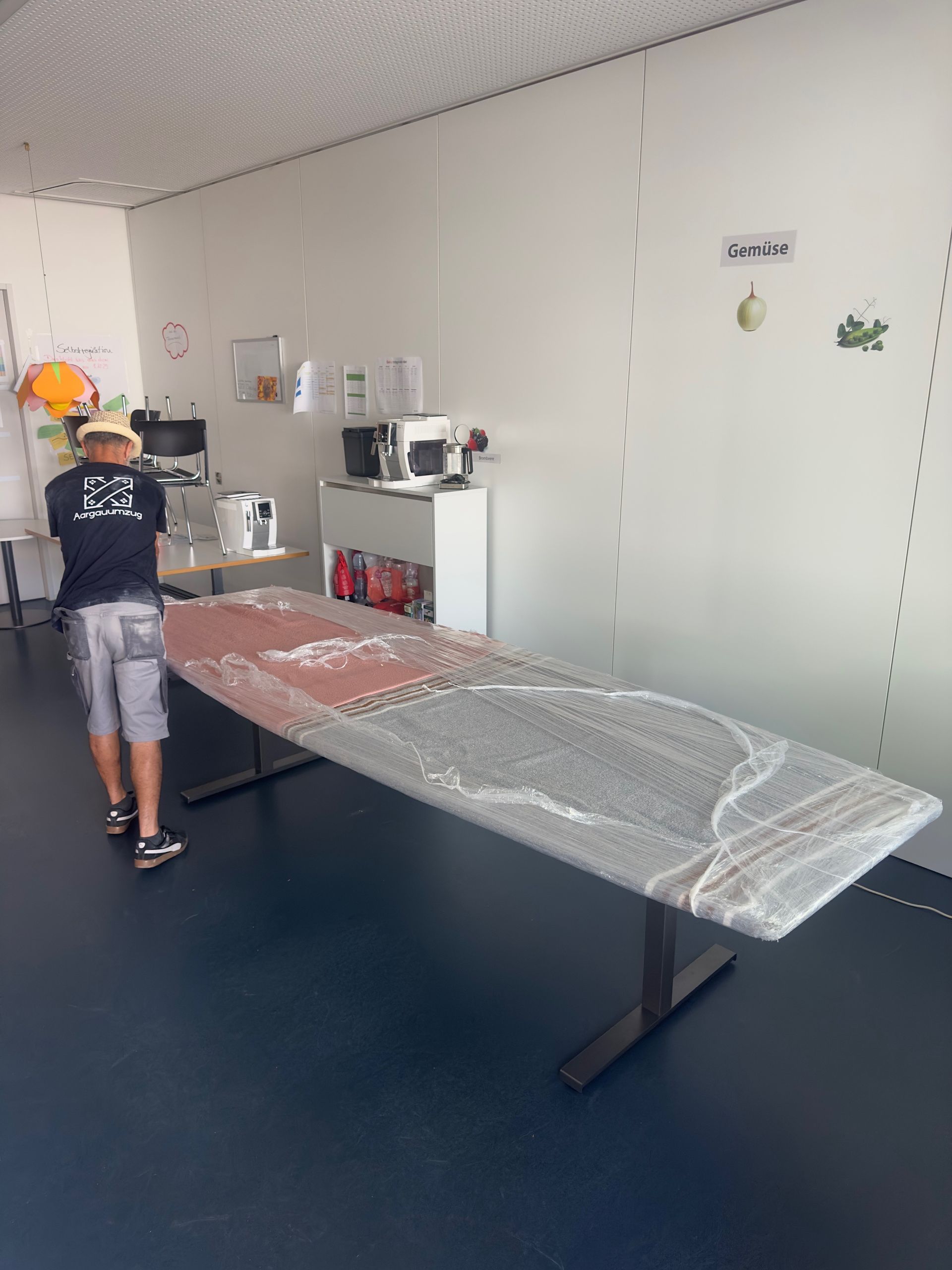 Wohnzimmer mit weißer Einrichtung, Küchenzeile und Person mit Rucksack