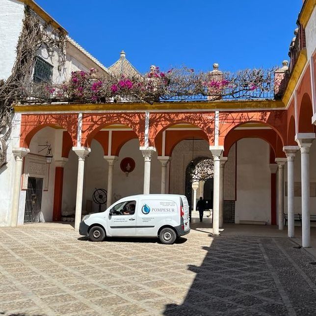 Una furgoneta blanca está aparcada en el patio de un edificio.