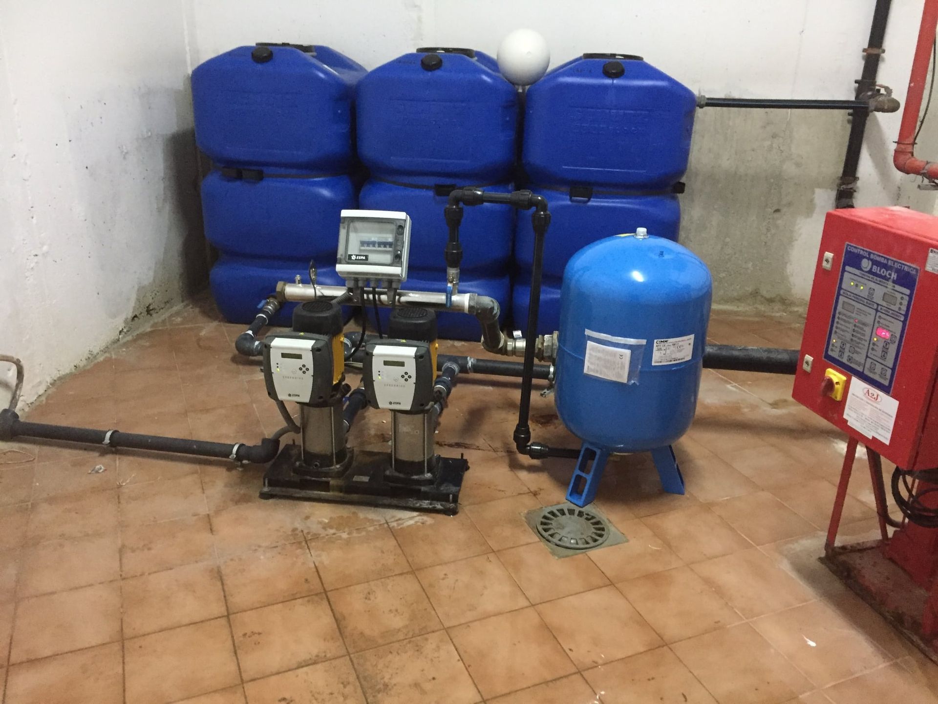 Una habitación con muchos barriles azules y una caja roja.