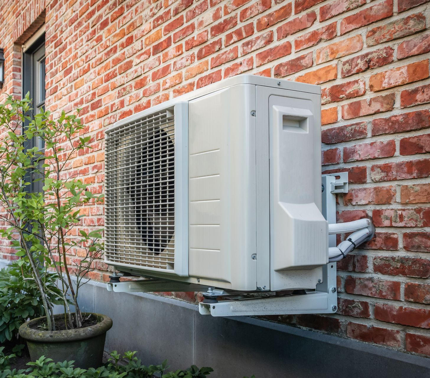 Une pompe à chaleur devant un mur en brique