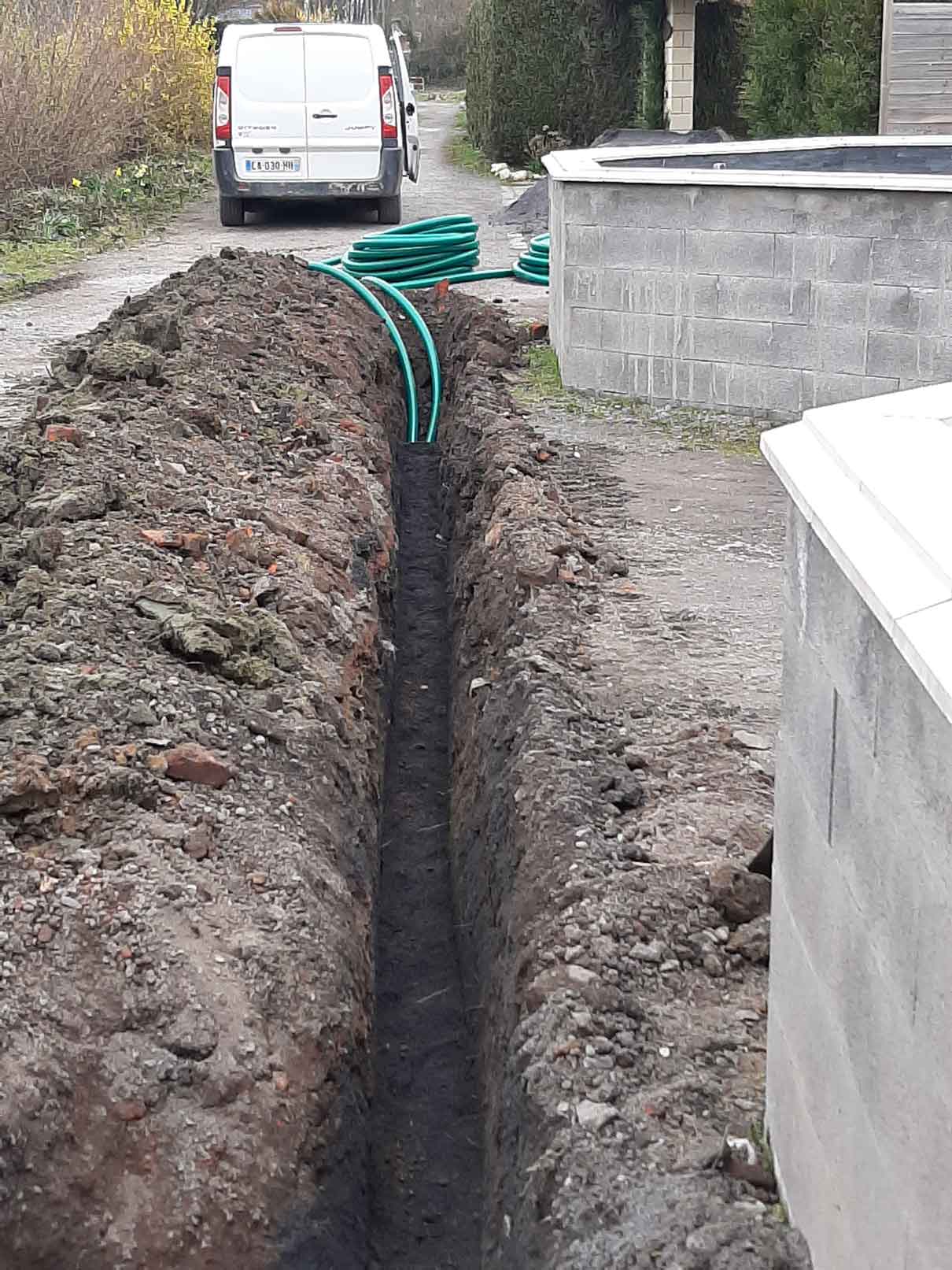 Des tuyaux enterré dans une tranché avec un camionette utilitaire en fond