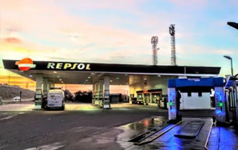 Una gasolinera Repsol con lavadero de coches, bajo el cielo del atardecer.