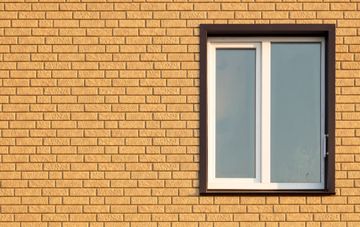 Ventana con marco blanco enmarcada en una pared de ladrillo amarillo.