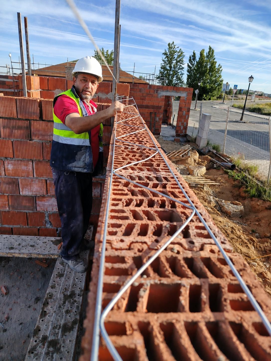 Obrero de la construcción alineando un muro de ladrillos con una cuerda en una obra.