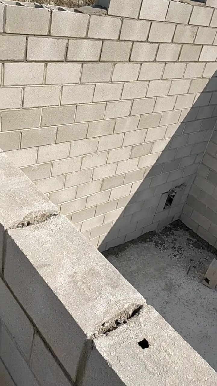 Muro de bloques de hormigón parcialmente construido y esquina de cimentación de hormigón