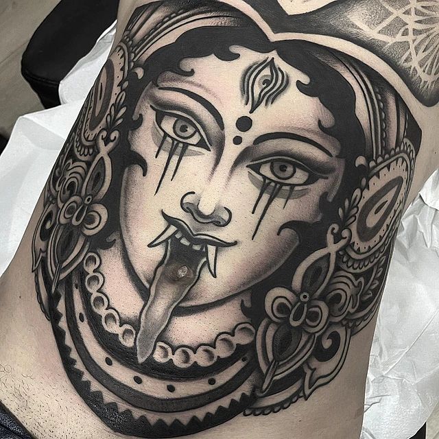 Un tatuaje en blanco y negro de la cara de una mujer con la lengua fuera.
