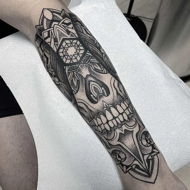 Un tatuaje en blanco y negro de una calavera en el antebrazo de una persona.