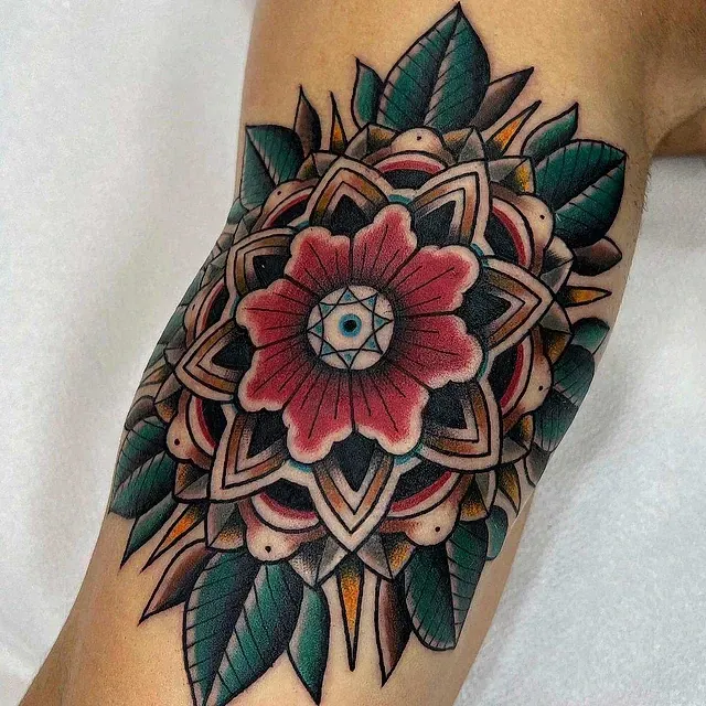 Un tatuaje de una flor con hojas en el brazo de una persona.