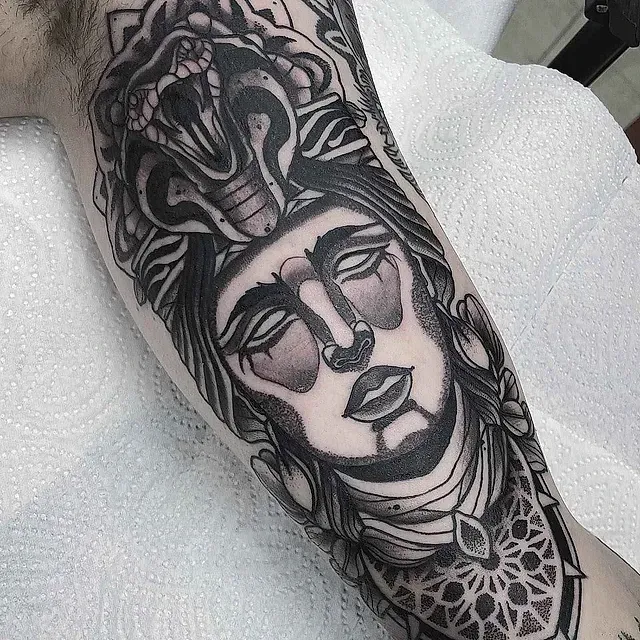 Un tatuaje en blanco y negro del rostro de una mujer con una corona en la cabeza.