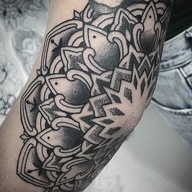 Un tatuaje en blanco y negro en el codo de una persona.