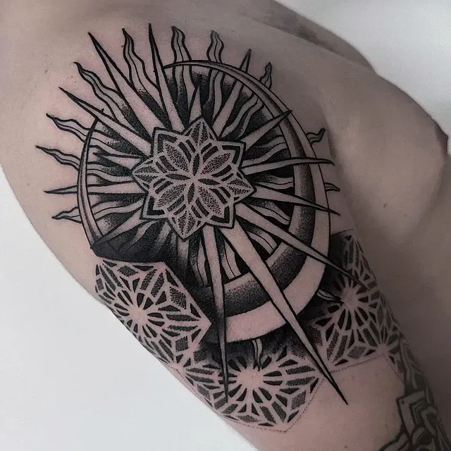 Un tatuaje en blanco y negro de una brújula en el brazo de una persona.