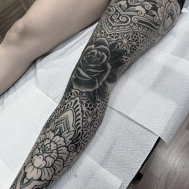 Una mujer acostada en una cama con un tatuaje en la pierna.