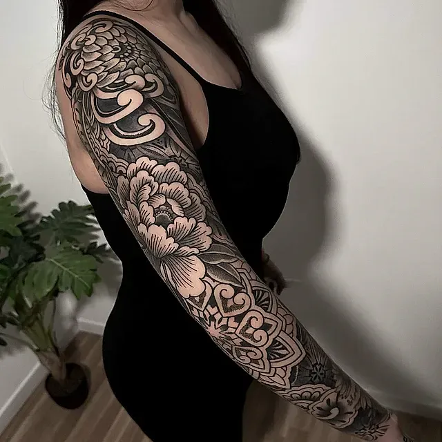 Una mujer tiene un tatuaje de manga completa en su brazo.