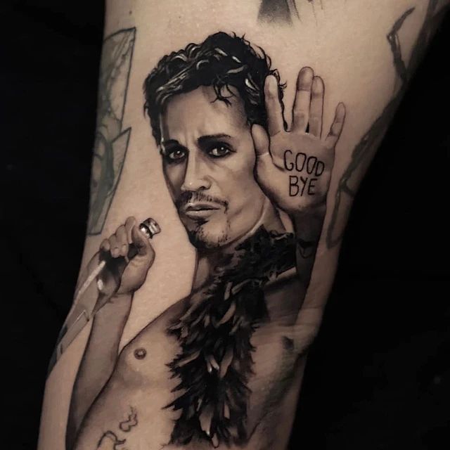 Un tatuaje de un hombre sosteniendo un micrófono y diciendo adiós.