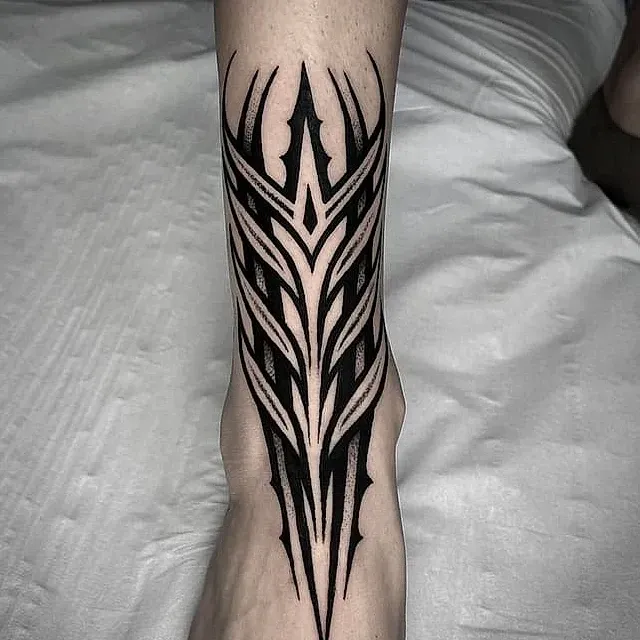 Un tatuaje en blanco y negro en la pierna de una persona.