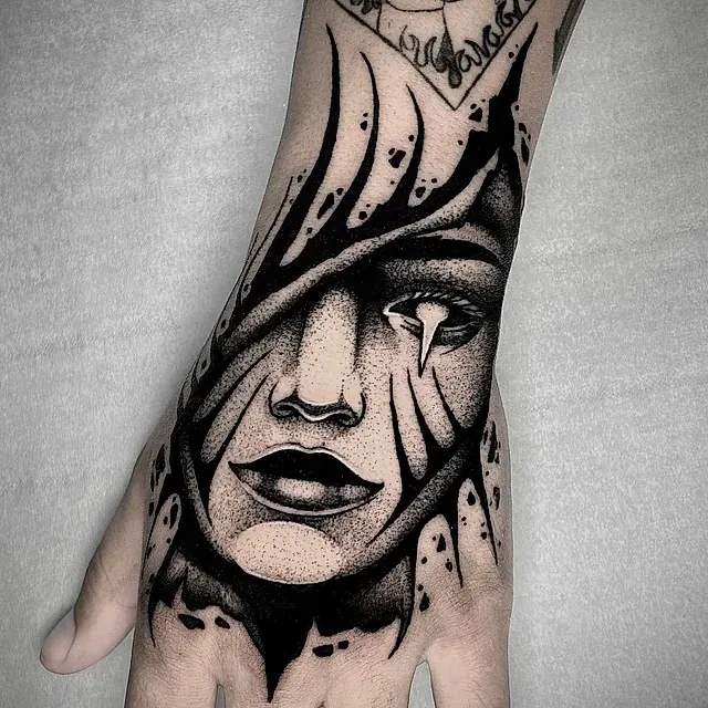 Un tatuaje en blanco y negro de la cara de una mujer en una mano.