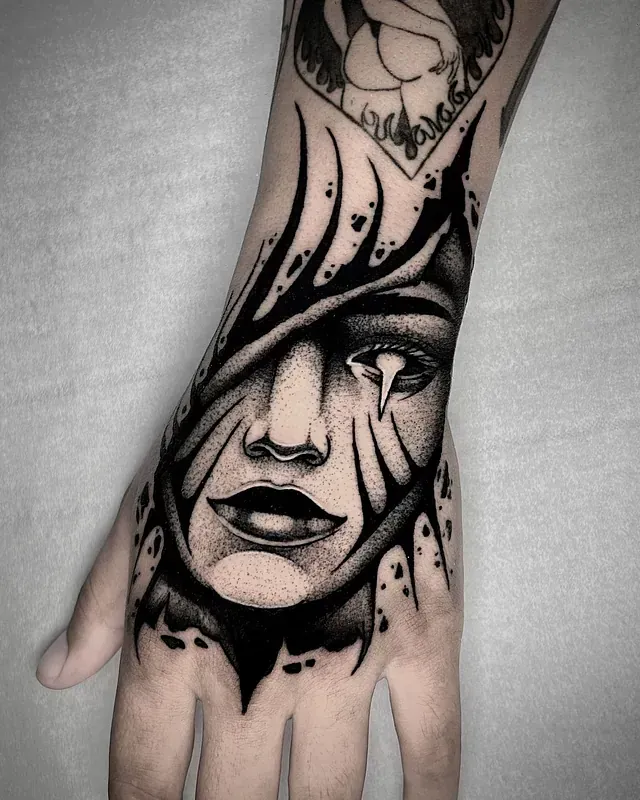 Un tatuaje en blanco y negro de la cara de una mujer en una mano.