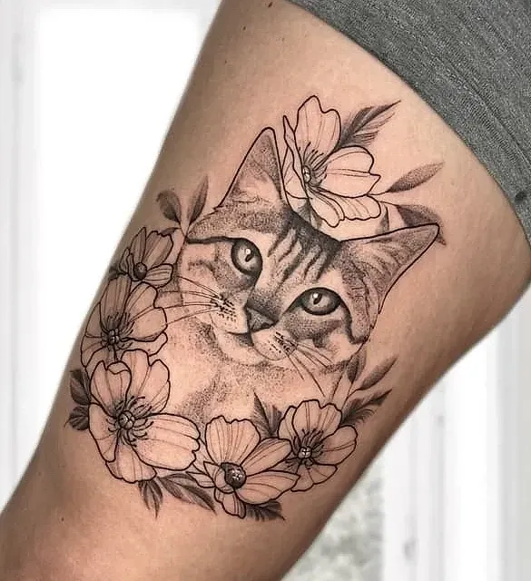 Un tatuaje en blanco y negro de un gato rodeado de flores.